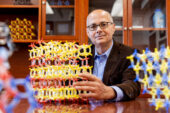 A seated man holds a chemical model