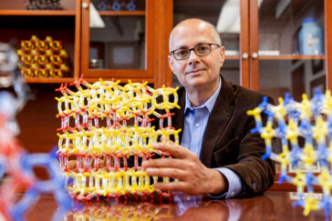 A seated man holds a chemical model