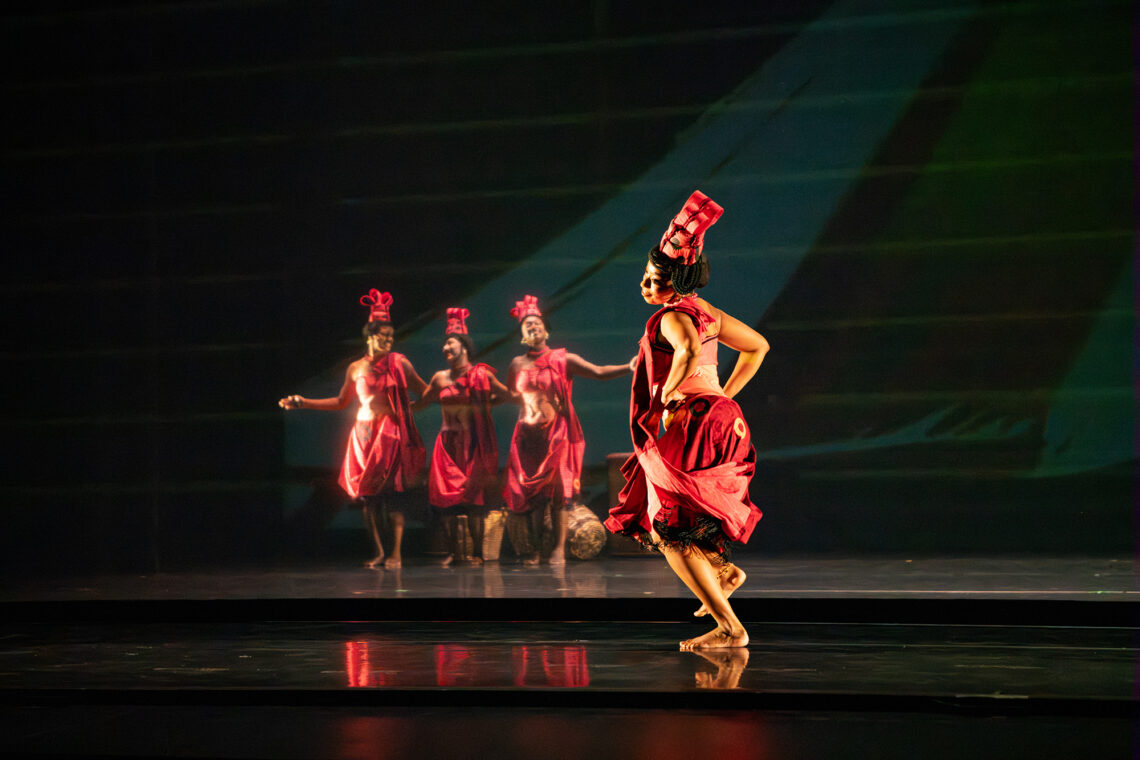 Photo of several dancers dressed in pink costumes and tall hats onstage.