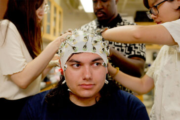 Photo of a young man being fitted with a swim cap studded with electrodes.