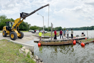 photo of a crane unloading two floating wetland structures into Lake Decatur.