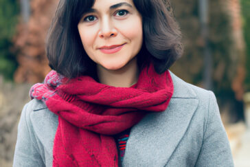Photo of Mahbubeh Moqadam standing outdoors wearing a red knit scarf and grey coat.