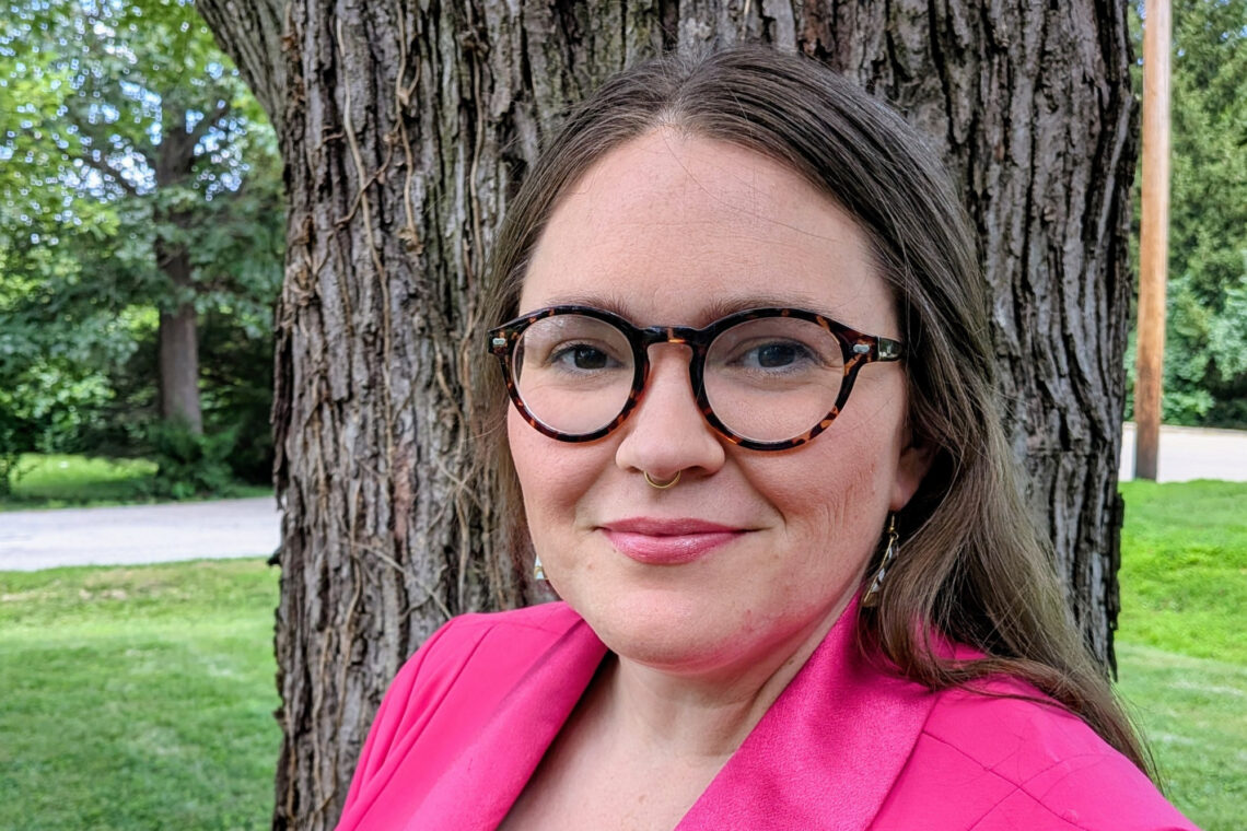 Headshot of Shannon Mason, standing outside in front of a tree and wearing a hot pink blazer.