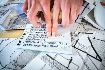 Photo of a pair of hands with fingers feeling a paper with Braille lettering.
