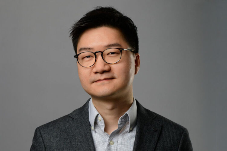 Studio photo of Wei Xu wearing a dark jacket and light blue button-down shirt.