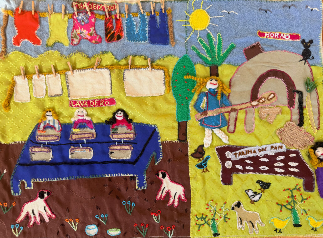 Photo of an arpillera showing women doing laundry and baking bread.