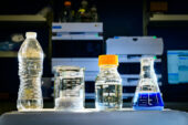 Photo from the lab of four containers. 1) a plastic bottle, 2) a beaker with shredded plastic, 3) a capped bottle with pyruvate and 4) a flask with blue dye.