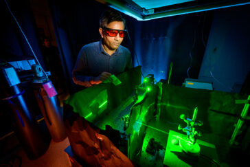 Researcher wearing protective glasses while using a laser to activate an specialized electrochemical reaction inside of an reaction cell.