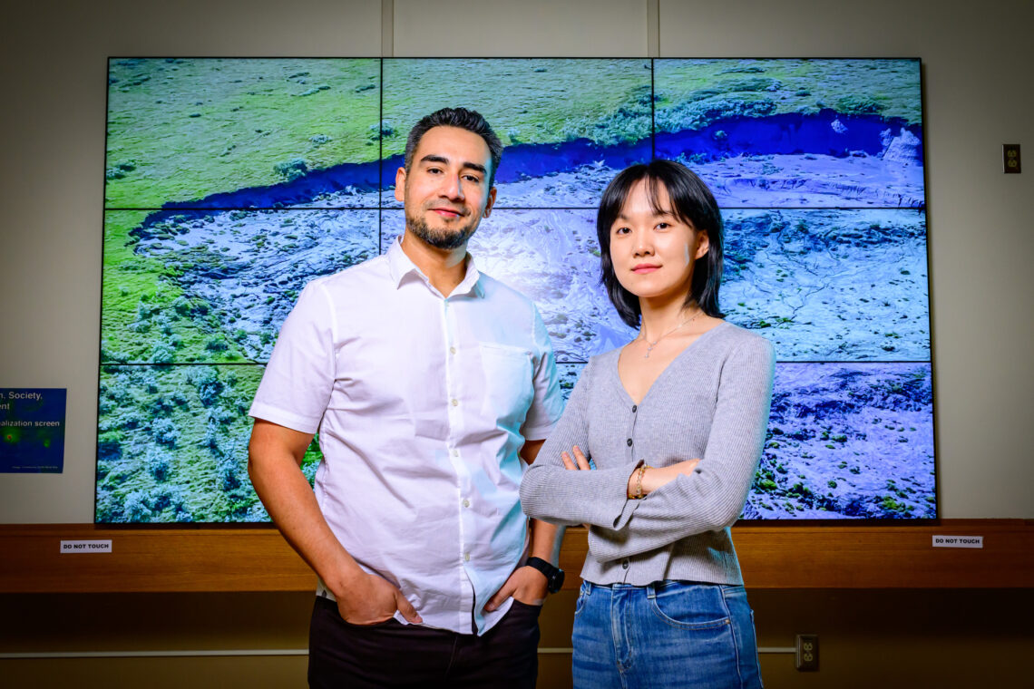 Photo of the researchers standing in front of a projected image of a permafrost slump.