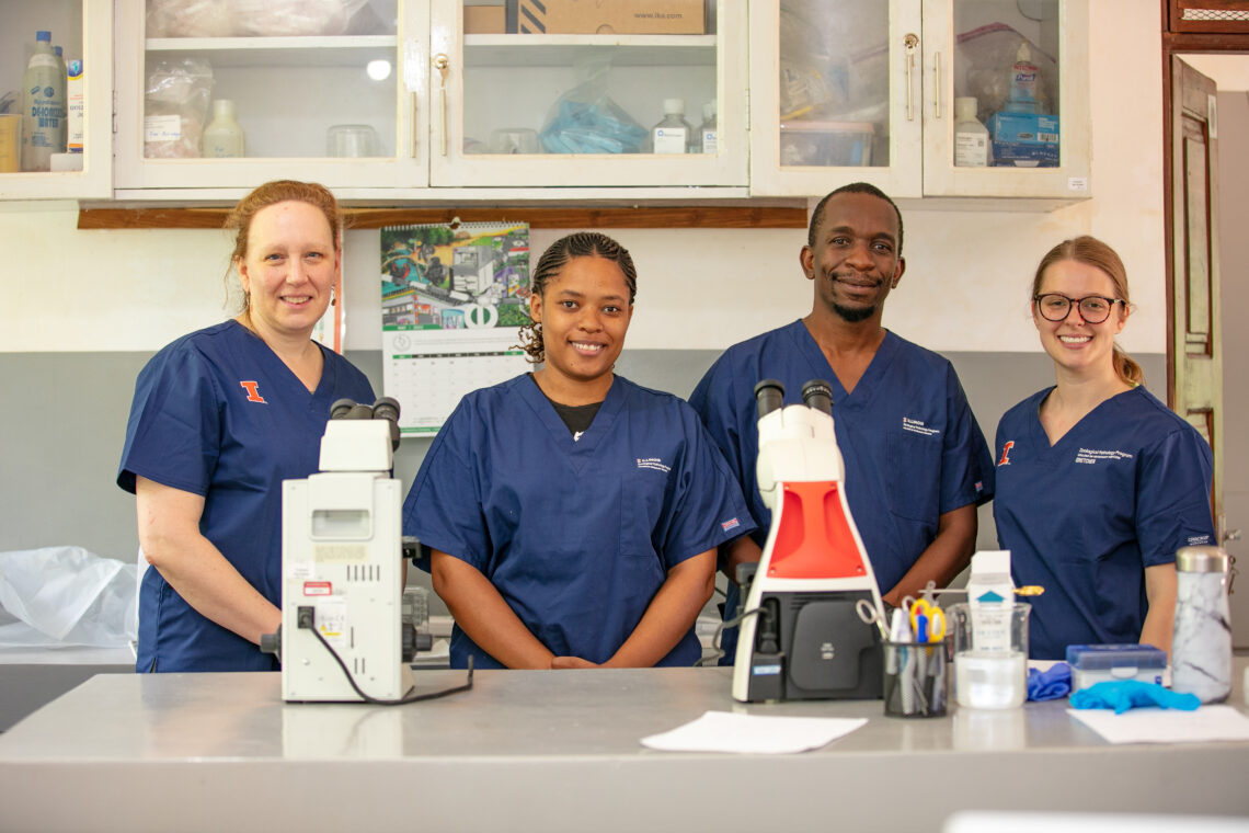 Photo of the team in scrubs in a laboratory, posing for the photo. 