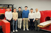 Six people stand in front of red MRI machines
