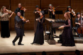 Photo of a group of violinists from Apollo's Fire standing and playing onstage.