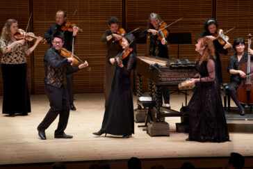 Photo of a group of violinists from Apollo's Fire standing and playing onstage.