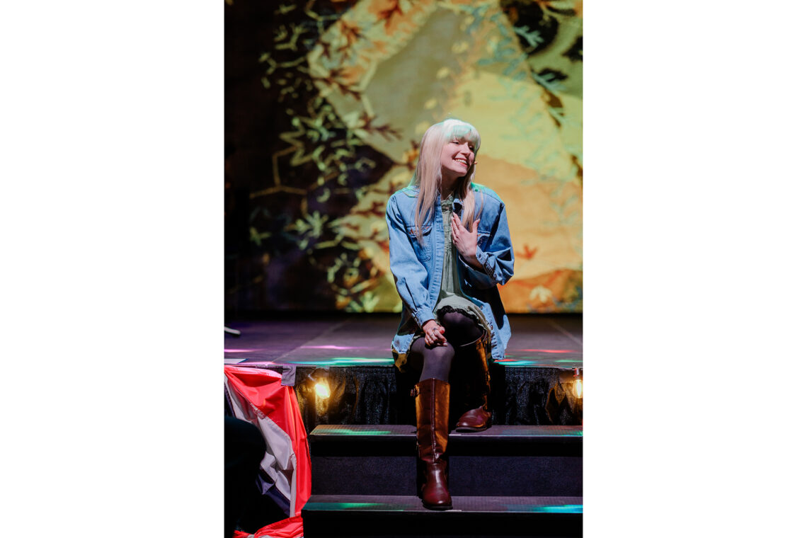 Photo of Catheryn Kuhar sitting on stage and singing.
