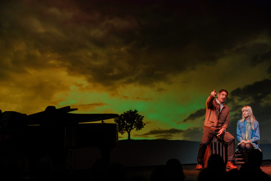 Photo of Nathan Gunn and Catheryn Kuhar performing on stage in front of a backdrop of a sunset.