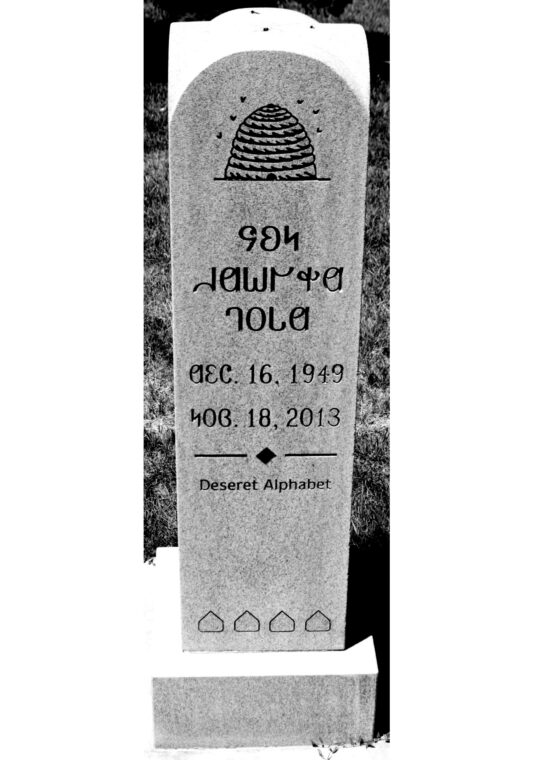 Photo of a grave marker with words written in the Deseret alphabet.