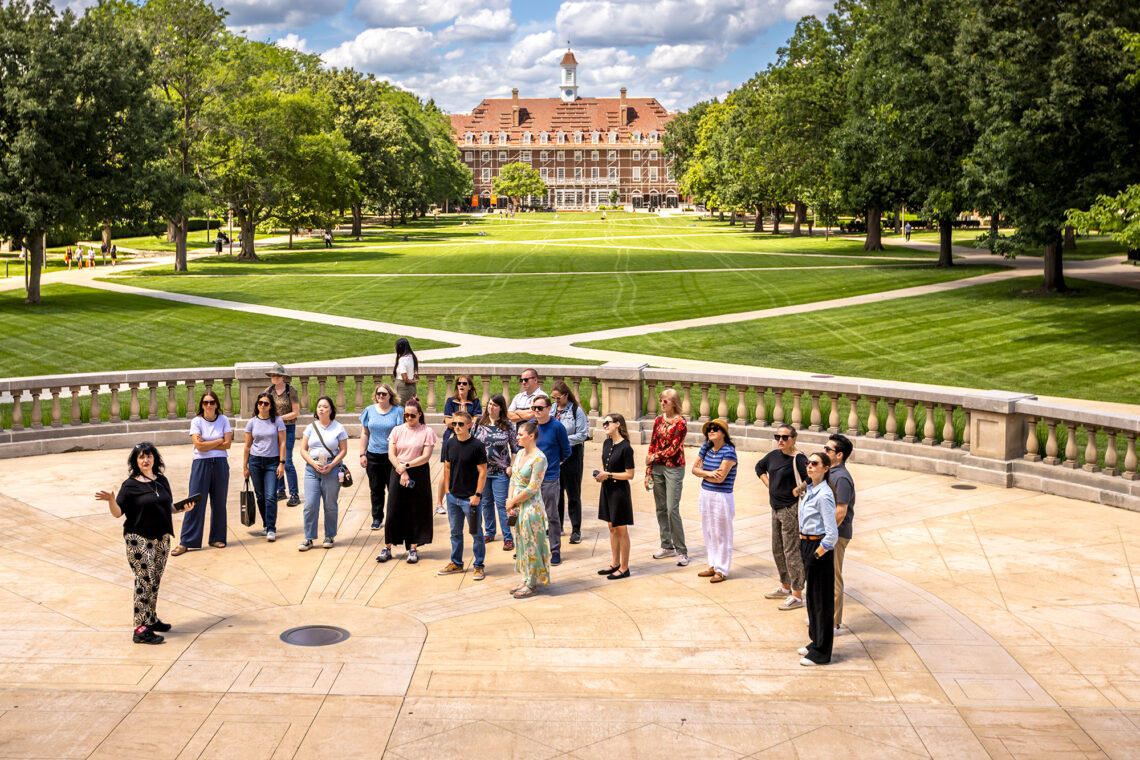 Photo of Lois Yoksoulian talking with a group of 20 on Foellinger Hall Plaza with a view of the Union in the distance.