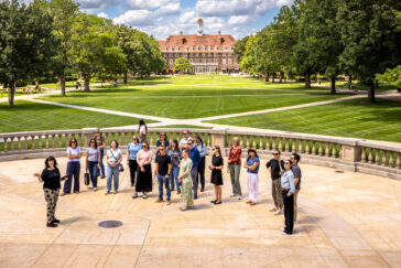 Photo of Lois Yoksoulian talking with a group of 20 on Foellinger Hall Plaza with a view of the Union in the distance.