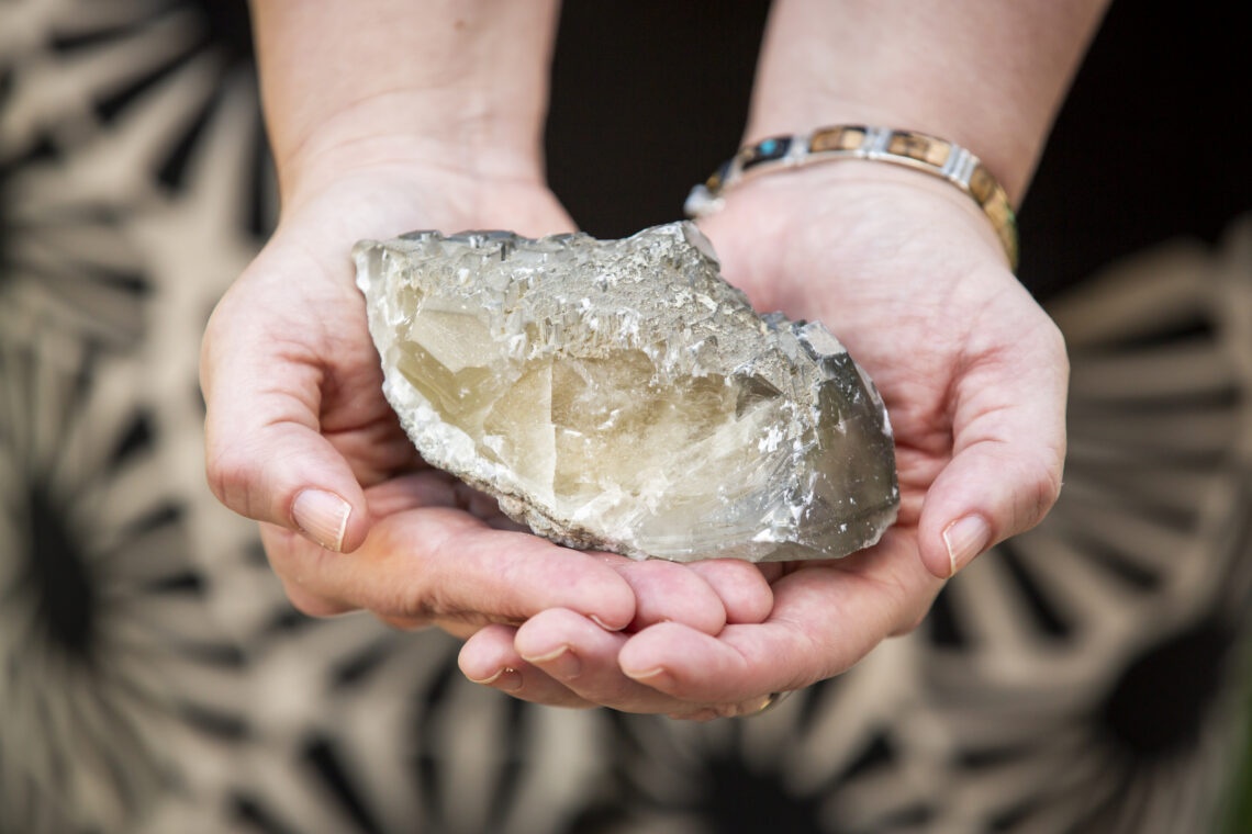 Photo of Lois Yoksoulian's hands holding a block of calcite.
