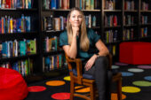 Jessica Gladstone seated in a chair with bookshelves full of books in the background.