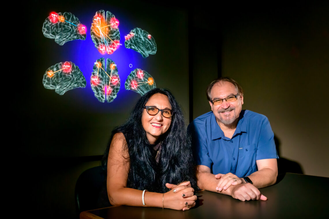 Photo of the researchers seated in front of a projected image of several brain regions activated during the study.