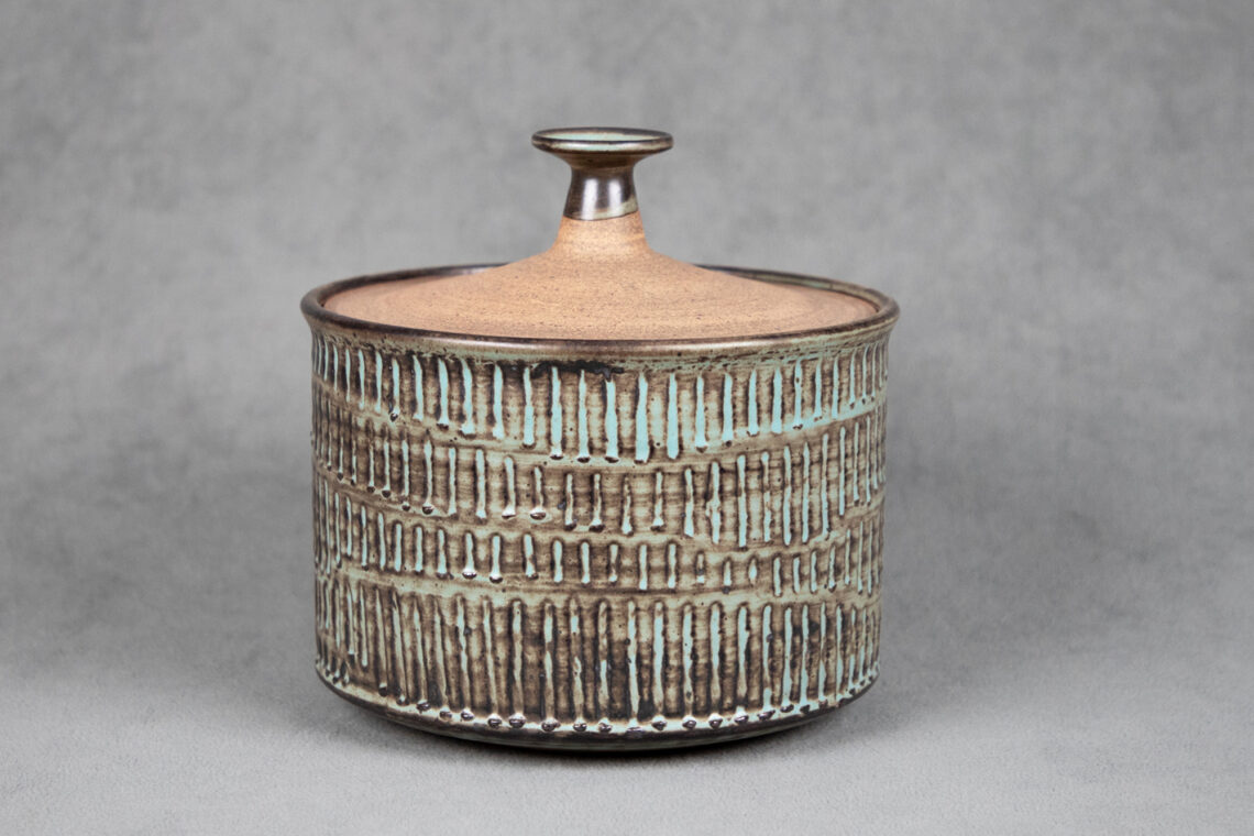 Photo of a tan ceramic casserole dish with seafoam green vertical stripes.