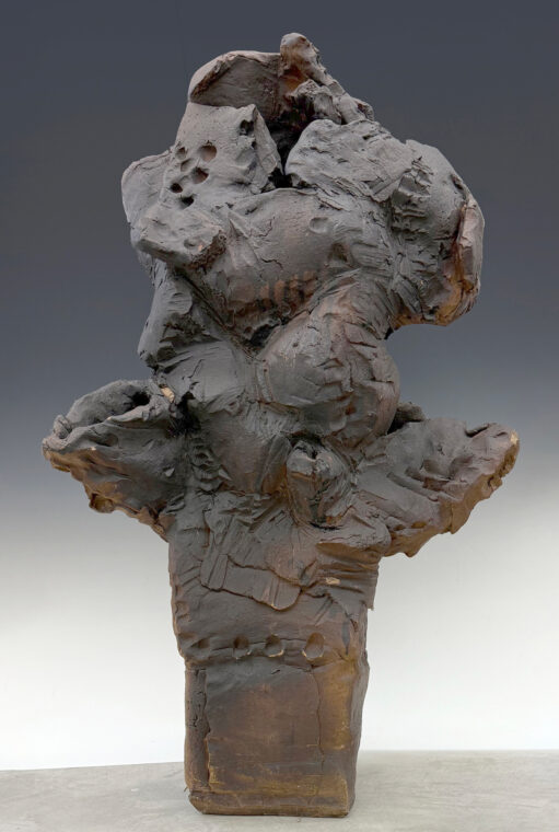 Photo of a large abstract brown-colored sculpture with finger marks in the clay.