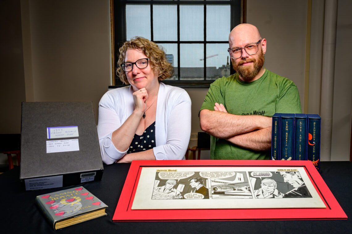 Photo of Lynne M. Thomas and Yusuf Hermes with several items from the Rare Book and Manuscript Library's collection of Ian Fleming and James Bond materials.