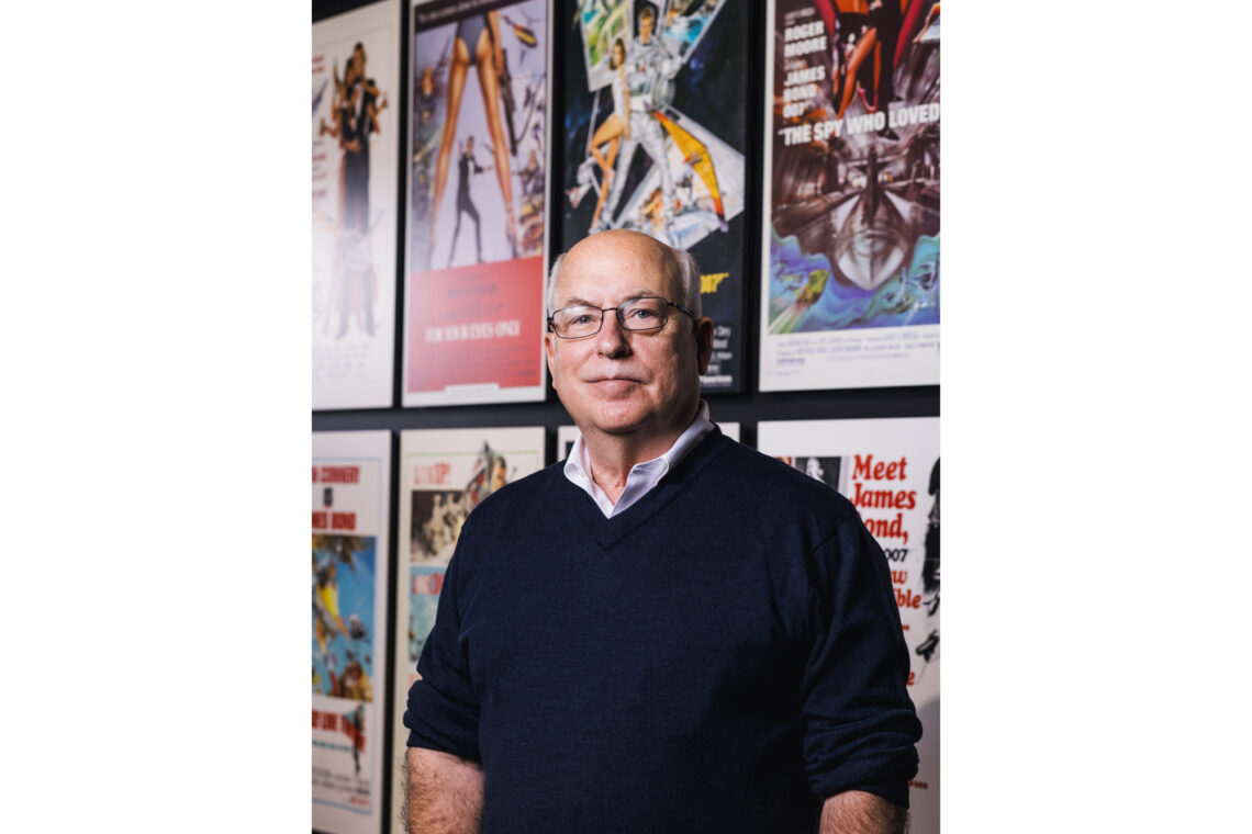 Photo of Michael VanBlaricum in front of posters for James Bond movies.