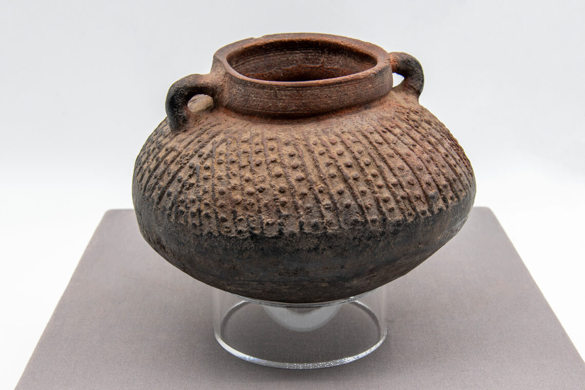 Photo of a brown ceramic pot with a texture of lines and dots.