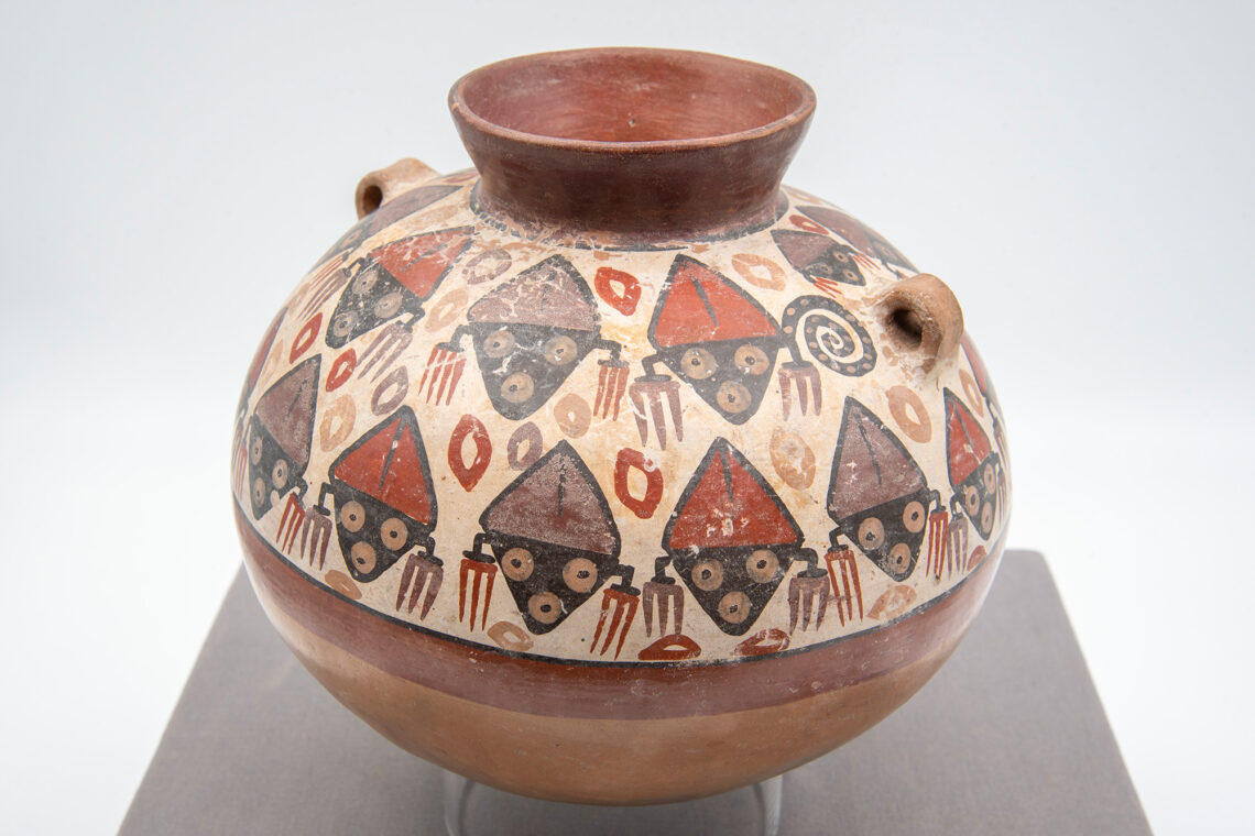 Photo of a ceramic pot decorated with abstract faces in browns and rusts.