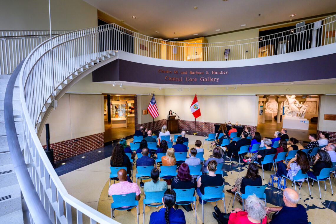 Photo of a group of people sitting in chairs and listening to a speaker at Spurlock Museum of World Cultures.