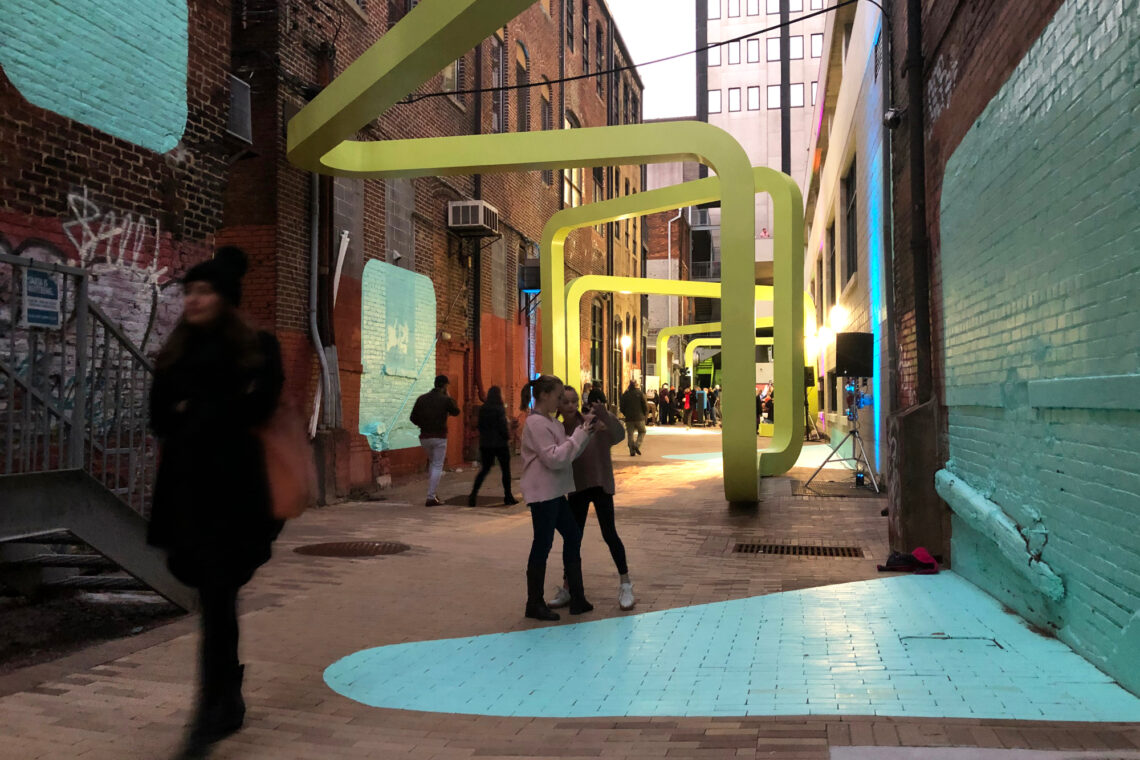 Photo of an alley with colorful paint and a sculpture through its length.