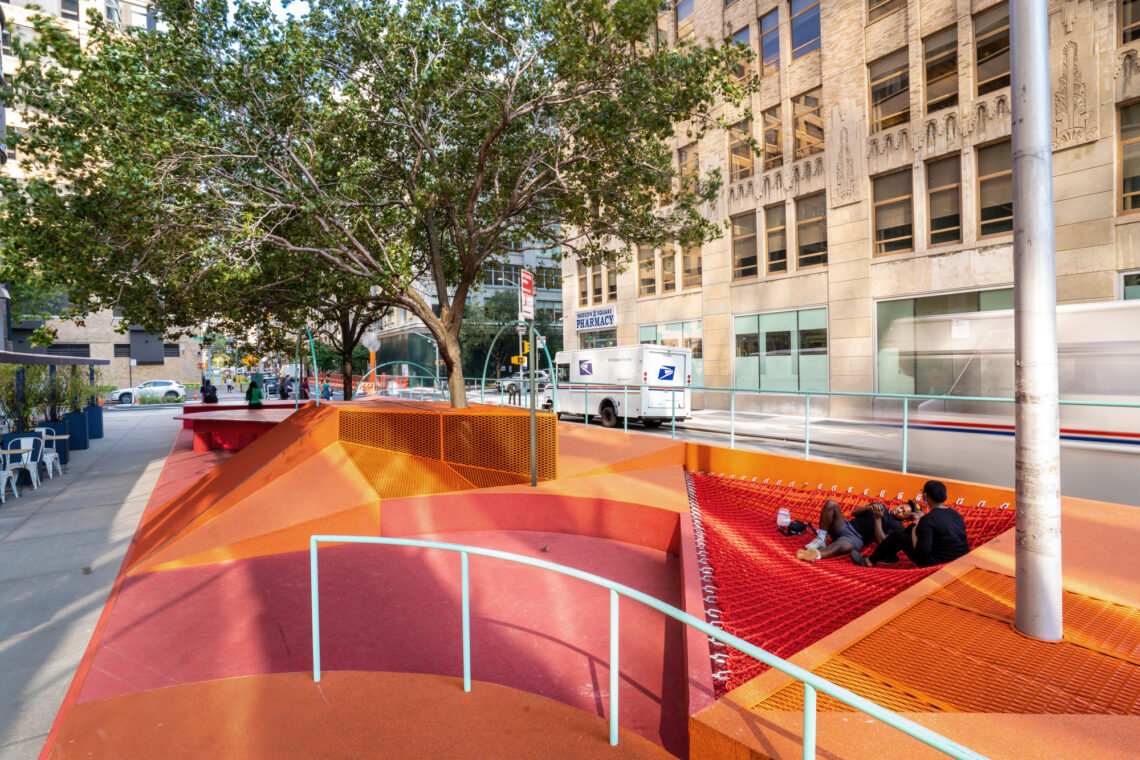 An image of a play area colored orange with netting and sloped ramps between a sidewalk and a street.
